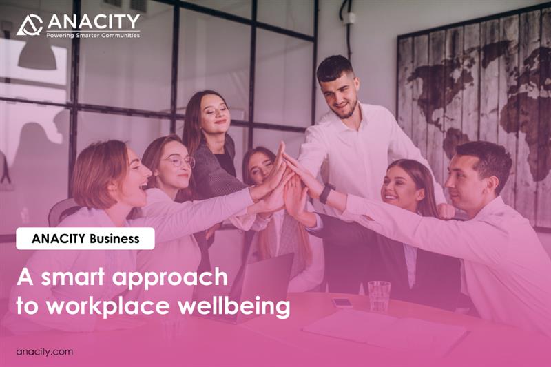 A picture in workplace with people joining hands. Text says ANACITY Business: A smart approach to employee wellbeing